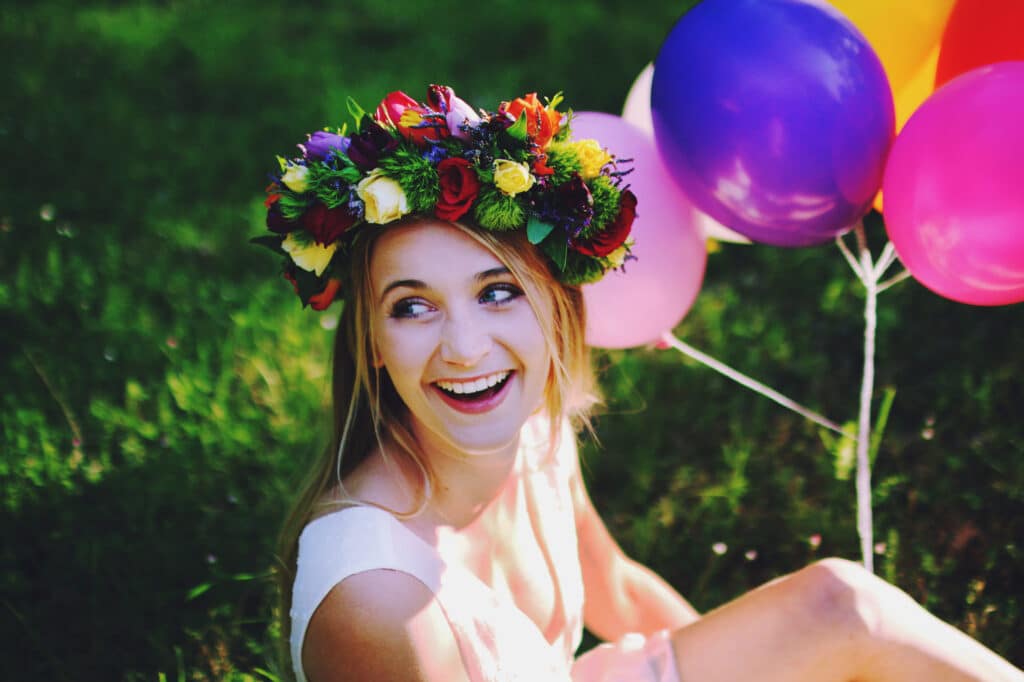 Une jeune mariée rayonnante, entourée de ballons colorés et d'une couronne de fleurs, incarne l'élégance et la joie d'un mariage romantique. Ce moment capturé évoque la magie d'un événement sur mesure, parfaitement organisé par 'By Mademoiselle C', votre wedding planner de luxe en Provence, Côte d'Azur et Corse. Avec des décors naturels enchanteurs, tels que des jardins luxuriants, chaque mariage devient une célébration.