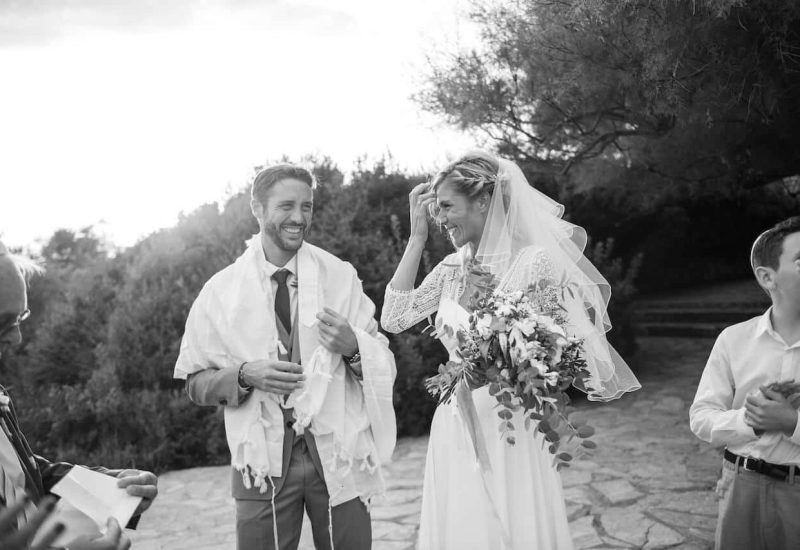A romantic scene of a happy couple at their wedding ceremony in Provence, capturing the essence of a grand celebration. This elegant moment illustrates By Mademoiselle C's expertise as a luxury wedding planner in exceptional locations. Surrounded by the natural beauty of the mountains, guests witness a tailor-made event, reflecting impeccable organization for an unforgettable day.