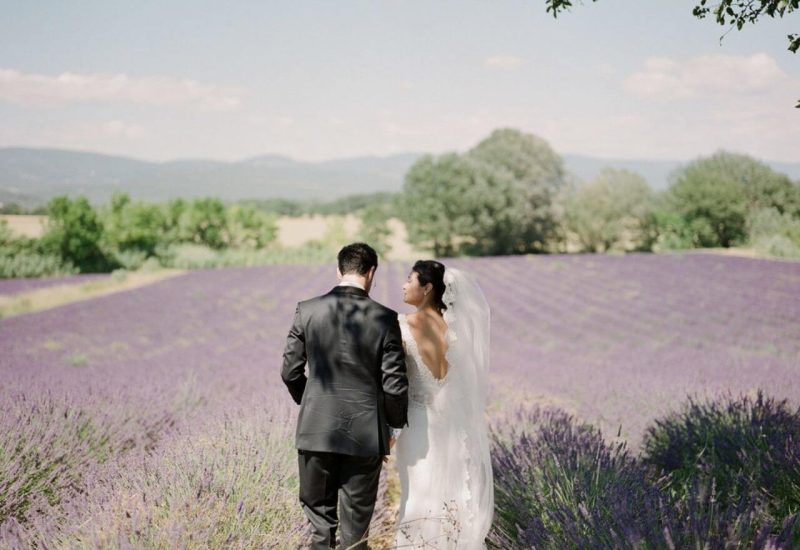 An elegant wedding ceremony in a lavender field in Provence, showcasing By Mademoiselle C's expertise. This romantic moment illustrates a grand celebration, where every detail is carefully orchestrated to create a unique event. The enchanting setting, with its lavender landscapes, evokes a sophisticated atmosphere, perfect for a bespoke wedding on a private estate. A luxury wedding experience that transforms every moment into an unforgettable experience.