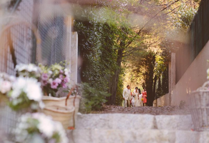 Une élégante cérémonie de mariage dans un domaine privé en Provence, où le couple, entouré de leurs proches, s'avance le long d'un chemin romantique, bordé de fleurs délicates. Cette image évoque une célébration grandiose et sur mesure, mettant en avant l'expertise de 'By Mademoiselle C' en tant que planificateur de mariage de luxe dans la Côte d'Azur et en Corse. L'atmosphère raffinée et sophistiquée, au