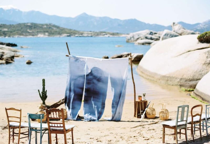Celebrate your dream wedding in an idyllic setting with By Mademoiselle C, your luxury wedding planner in Provence, French Riviera and Corsica. This romantic scene, with elegant chairs on a golden beach, evokes a grand waterfront ceremony. Imagine a tailor-made event, surrounded by picturesque landscapes and majestic rocks, perfect for a unique celebration.
