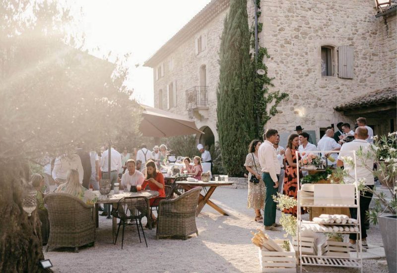 An elegant outdoor wedding on a private estate in Provence, where guests savor precious moments in a romantic atmosphere. Golden sunlight highlights the refined details of a bespoke celebration, with carefully laid tables surrounded by lush gardens. This exceptional setting, ideal for a grand event, is a testament to By Mademoiselle C's expertise in planning luxury weddings, making every moment an unforgettable experience.