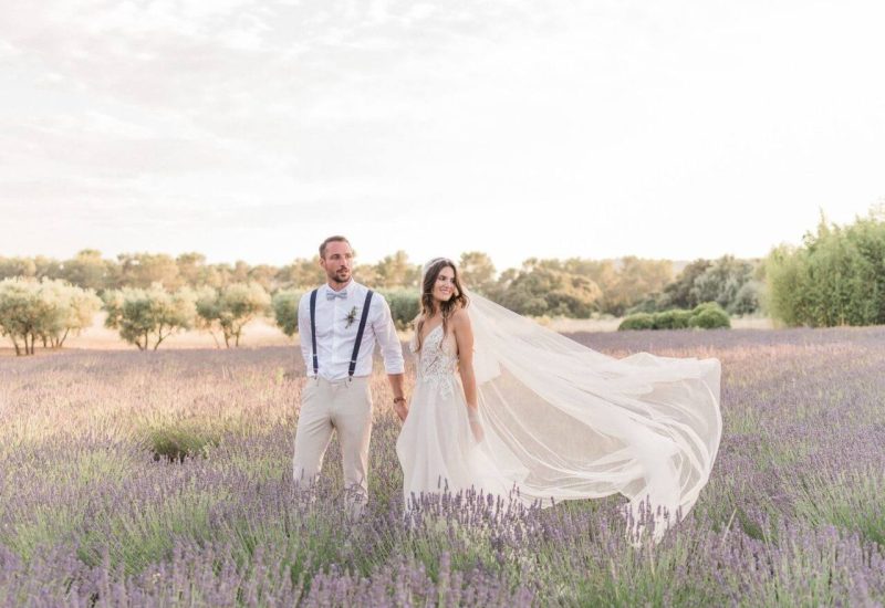 An elegant couple stand hand-in-hand in the middle of a lavender field, embodying the magic of a romantic wedding in Provence. This captivating scene perfectly illustrates By Mademoiselle C's expertise in planning luxury weddings. With enchanting landscapes and a sophisticated atmosphere, every detail contributes to creating a unique celebration. Whether for a grand ceremony or a bespoke event, this idyllic setting