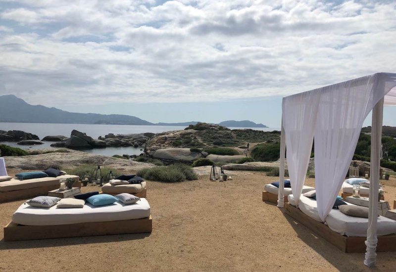 Un cadre romantique pour un mariage de luxe en Corse, avec des lits de jour élégants en bois, ornés de coussins doux, offrant une vue imprenable sur la mer. Ce lieu exceptionnel, niché entre les rochers et la nature, est parfait pour une célébration grandiose. By Mademoiselle C se spécialise dans l'organisation sur mesure d'événements uniques, créant des souvenirs inoubliables pour des couples en quête d'une expérience de mariage romant