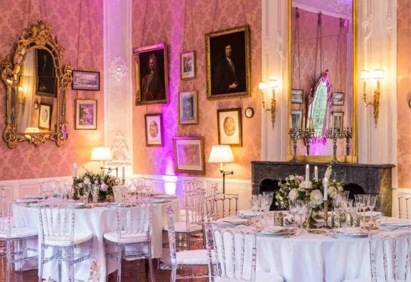 An elegant reception room adorned with gilded mirrors and refined decorations, perfect for a luxury wedding in Provence. The carefully laid tables, surrounded by transparent chairs, evoke a romantic and sophisticated atmosphere. This unique setting, ideal for a grand ceremony, underlines By Mademoiselle C's expertise in the organization of tailor-made weddings. With delicate floral decorations, this scene evokes a romantic, sophisticated atmosphere.