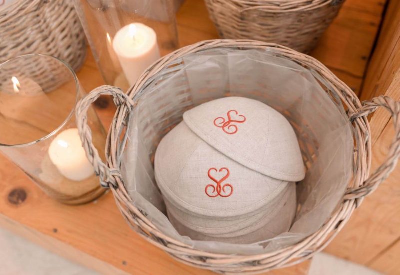 Wicker basket containing elegant accessories for a luxury wedding, with candles creating a romantic atmosphere. Ideal for tailor-made weddings in Provence, the French Riviera and Corsica, this sophisticated setting evokes a grand ceremony on a private estate. Every detail contributes to a unique celebration, making this moment a dream come true for couples looking for an unforgettable experience.