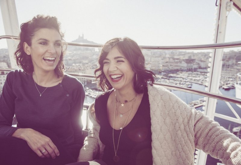 Deux femmes rayonnantes, profitant d'un moment joyeux dans une ambiance élégante, symbolisent l'esprit d'un mariage romantique. Avec en arrière-plan le port animé de Marseille, cette image évoque l'exclusivité des événements organisés par By Mademoiselle C, un expert en planification de mariages de luxe en Provence, Côte d'Azur et Corse. Chaque sourire reflète l'excitation d'une célébration grandiose, où des lieux exceptionnels.
