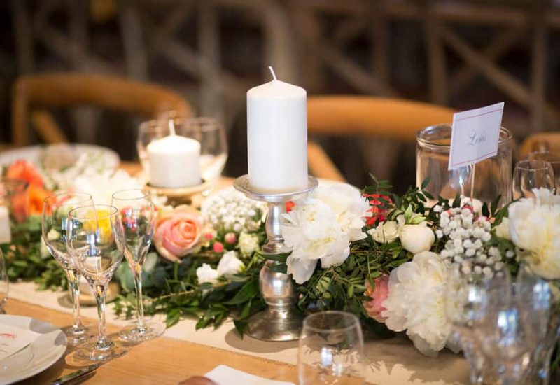 Elegantly laid table for a luxury wedding, adorned with delicate flowers and candles, creating a romantic atmosphere. This bespoke event, organized by By Mademoiselle C, takes place in an idyllic setting in Provence, showcasing exceptional venues for a grand celebration. The refined decor and meticulous details promise an unforgettable experience for a dream wedding on a private estate. A truly unique event,