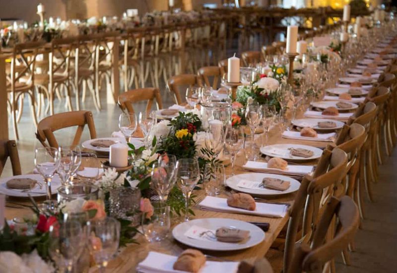 An elegantly set table for a grand event, featuring a romantic and sophisticated decor. This perfect setting for a luxury wedding in Provence, the French Riviera or Corsica underscores By Mademoiselle C's expertise in organizing tailor-made celebrations. Floral centerpieces and candles create an intimate atmosphere, ideal for an exceptional ceremony on a private estate. Every detail is thought out to offer an unforgettable experience, transforming