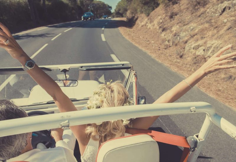 A radiant couple in a convertible car, celebrating their dream wedding in the picturesque landscapes of Provence. With arms raised to the sky, they embody the spirit of a grand and romantic ceremony, perfectly orchestrated by By Mademoiselle C. This image evokes a unique celebration, blending luxury and elegance, while highlighting the sophisticated atmosphere of sun-drenched roads leading to private estates and