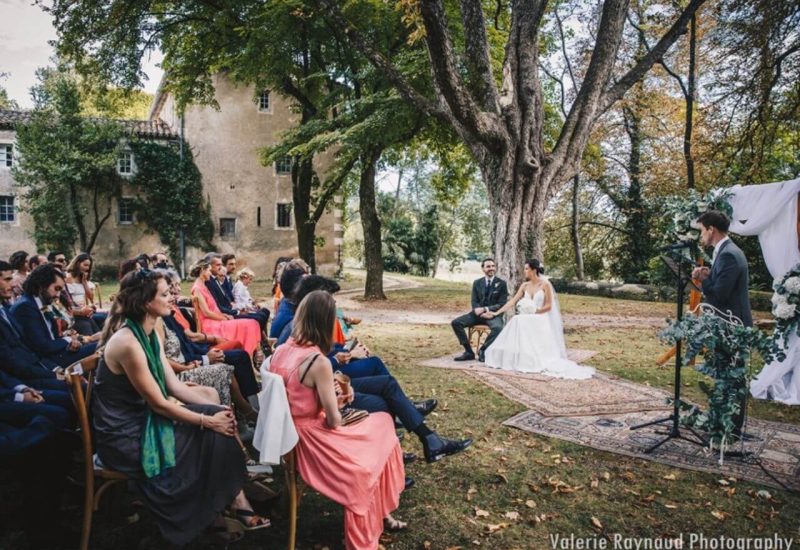 Romantic outdoor ceremony, organized by By Mademoiselle C, in an idyllic Provence setting. This bespoke wedding, nestled in a private estate, offers an elegant and sophisticated atmosphere. Tastefully attired guests watch the grand event under a majestic tree, while the couple beams with happiness. An unforgettable moment for a unique celebration, featuring the expertise of By M