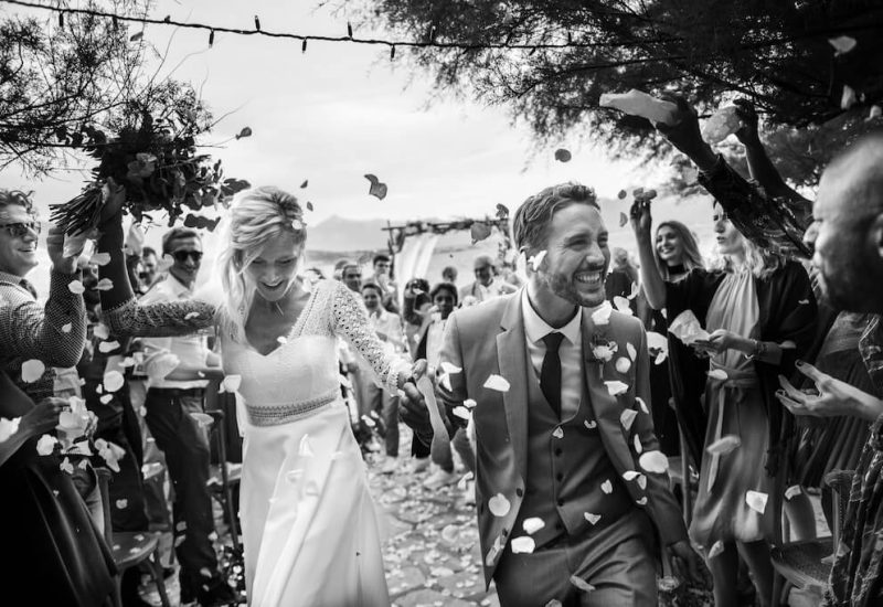 A romantic celebration of a luxury wedding in Provence, with the couple beaming under a shower of petals, surrounded by friends and family. This captured moment illustrates By Mademoiselle C's expertise in organizing bespoke ceremonies in exceptional locations. The elegant and sophisticated atmosphere of this event makes every wedding a unique moment, perfect for a grand celebration in the heart of the Côte d'Azur.