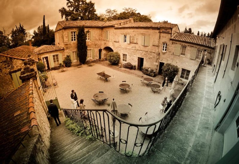 Une élégante cour intérieure d'un domaine privé, idéale pour une cérémonie de mariage romantique en Provence. Ce cadre sophistiqué, entouré de verdure, offre un espace parfait pour une célébration grandiose. Avec ses pierres anciennes et son atmosphère chaleureuse, cet endroit est l'incarnation d'un mariage sur mesure. Les invités profitent d'une expérience unique dans ce lieu exceptionnel, créant des souvenirs inoubliables lors d'un événement de luxe. 'By Mademoiselle