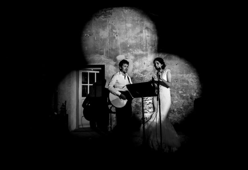A couple sings at a romantic ceremony in an elegant setting, showcasing By Mademoiselle C's expertise as a wedding planner in Provence, the French Riviera and Corsica. This intimate scene evokes a grand celebration, where every detail is carefully orchestrated to create a unique event. The sophisticated atmosphere, accentuated by stone walls, underlines the importance of an exceptional venue, perfect for a tailor-made wedding.