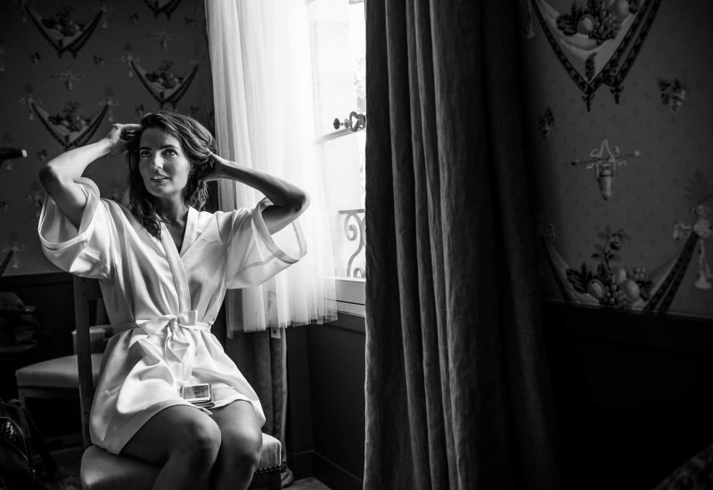 An elegant bride prepares in a romantic, sophisticated atmosphere, embodying the essence of a luxury wedding. In an intimate setting, rich in detail, she evokes a grand celebration, ideal for a bespoke event. This captured moment reflects By Mademoiselle C's expertise in planning exceptional weddings in Provence, the French Riviera and Corsica. The soft light and refined decor soul