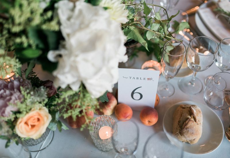 An elegantly laid table for a luxury wedding, adorned with delicate flowers and fresh fruit, evoking a romantic atmosphere. This setting is ideal for a bespoke event on a private estate in Provence, the French Riviera or Corsica. Every detail, from the refined glassware to the sparkling candles, underlines By Mademoiselle C's expertise in creating grandiose celebrations. Perfect for a dream wedding, this ag