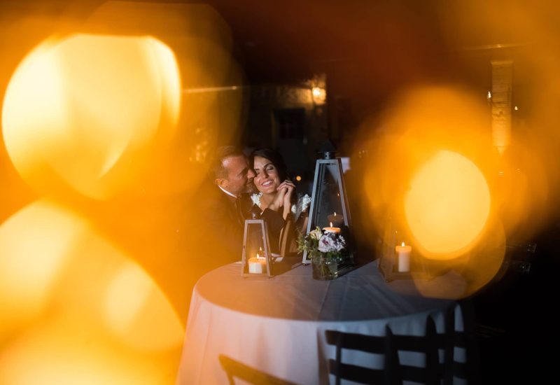 A romantic scene of a happy couple at a wedding celebration in an elegant setting, illustrating By Mademoiselle C's expertise as a wedding planner in Provence, French Riviera and Corsica. The soft light of lanterns and candles creates a warm, intimate atmosphere, perfect for a grand event. This moment is a testament to a luxury wedding, where every detail is tailor-made for a unique experience. The refined décor and