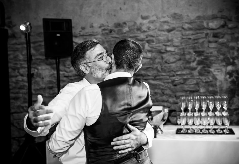 A moving moment at a wedding on a private estate in Provence, where a father and son share a touching dance. This luxury celebration, organized by By Mademoiselle C, embodies the essence of a bespoke wedding, combining elegance and romance. Surrounded by stone walls, the sophisticated atmosphere of this unique event showcases grand party elements, creating unforgettable memories.