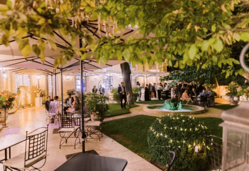 An elegant outdoor wedding celebration in a romantic garden, showcasing 'By Mademoiselle C''s expertise as a luxury wedding planner in Provence, the French Riviera and Corsica. The sophisticated atmosphere, enhanced by soft lighting and delicate decorations, creates the ideal setting for a grand event. This bespoke wedding underlines the importance of exceptional venues, such as this private estate, for