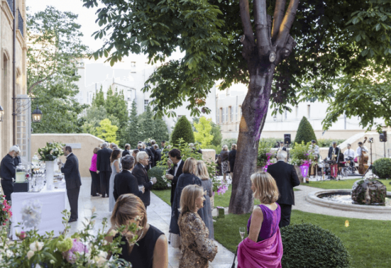 Elegant wedding in a refined garden, featuring By Mademoiselle C's expertise as Wedding Planner in Provence, French Riviera &amp; Corsica. This grandiose celebration, surrounded by lush plants and colorful flowers, evokes a romantic and sophisticated ambience. Guests, dressed to the nines, enjoy a tailor-made event in an exceptional private estate, creating an unforgettable experience for a luxury wedding.