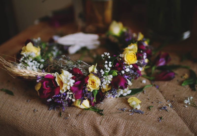 Elegant floral wreath featuring yellow roses and deep purple flowers, symbolizing a romantic, luxurious wedding. Perfect for bespoke arrangements in exceptional locations in Provence, the French Riviera and Corsica, this centerpiece evokes a grand celebration. The refined details of this wreath illustrate By Mademoiselle C's expertise in creating unique and memorable weddings, transforming every event.