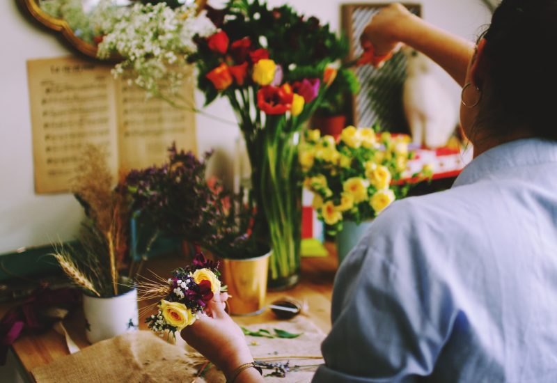 A florist creating an elegant bouquet in a romantic setting, perfect for a luxury wedding in Provence, French Riviera and Corsica. This inspiring space, filled with vibrant flowers, evokes unique, bespoke celebrations. With a focus on staging grandiose ceremonies on private estates, every detail contributes to designing an exceptional event. Floral creativity showcases 'By Mademoiselle C' expertise