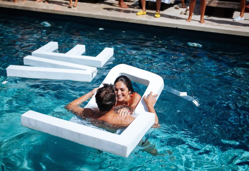 A joyful couple embrace in a luxurious pool, surrounded by a romantic and elegant atmosphere, perfectly illustrating By Mademoiselle C's expertise in wedding planning. This unique moment evokes a grand celebration, ideal for a bespoke wedding in Provence, the French Riviera and Corsica. With refined design elements and exceptional venues, this scene captures the essence of a dream ceremony.
