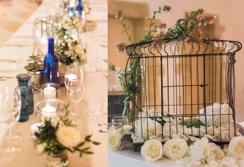 Une élégante table de réception, décorée de verres raffinés et de bouteilles en verre bleu, évoque une ambiance romantique pour un mariage de luxe en Provence. Les bougies illuminent délicatement le décor, tandis que des fleurs blanches ajoutent une touche de sophistication. Ce cadre idyllique est parfait pour une cérémonie grandiose dans un domaine privé, où chaque détail est méticuleusement organisé pour créer un événement sur mesure. Les éléments de décoration, comme la cage ornée