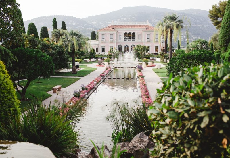 Un cadre romantique et élégant pour un mariage de luxe à Provence, Côte d'Azur et Corse, mettant en valeur un domaine privé exceptionnel. Ce jardin somptueux, avec ses fontaines et ses fleurs colorées, offre l'environnement parfait pour une célébration grandiose. La beauté naturelle des montagnes en arrière-plan crée une ambiance idéale pour un événement sur mesure, garantissant une expérience inoubliable pour un mariage de rêve. 'By Mademoiselle C' excelle dans l'organisation
