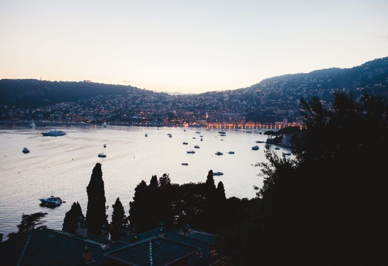 Vue romantique sur la Côte d'Azur au crépuscule, idéale pour un grand mariage de luxe. Ce paysage enchanteur, avec ses bateaux flottant sur l'eau scintillante, évoque une célébration sur mesure dans un cadre exceptionnel. Parfait pour une cérémonie grandiose dans un domaine privé ou un jardin élégant, chaque détail est soigneusement orchestré par By Mademoiselle C, créateur de mariages uniques en Provence, Côte d'Azur et Corse. Transform