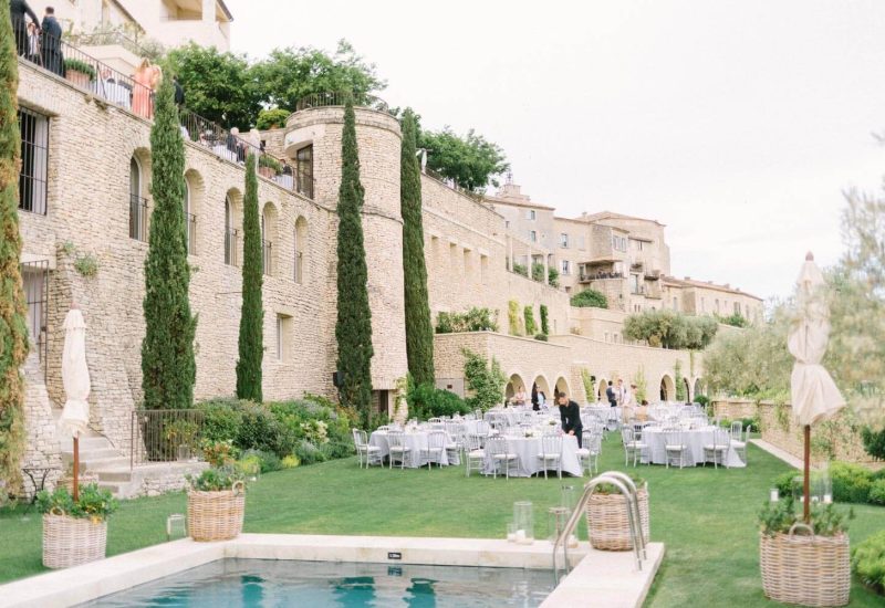 An elegant setting for a wedding celebration on a private estate in Provence, where scenic beauty blends with a romantic atmosphere. This image illustrates a grand event on a verdant lawn, surrounded by majestic cypress trees and golden stones, ideal for a luxury wedding. The carefully laid tables reflect By Mademoiselle C's expertise in organizing tailor-made ceremonies. An exceptional venue for a