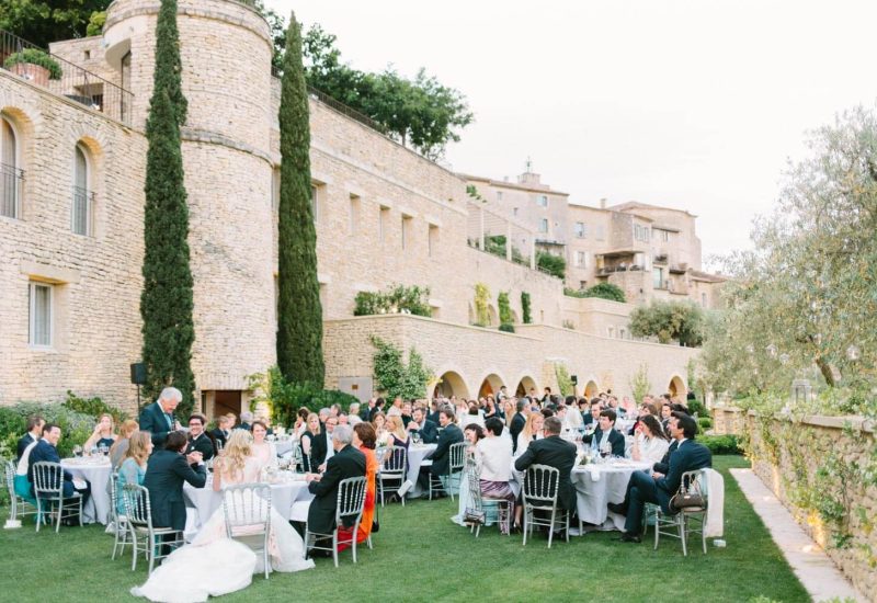 An elegant open-air dinner on a private estate in Provence, where refined guests celebrate a luxury wedding. The scene exudes romance, surrounded by picturesque landscapes typical of the French Riviera. This bespoke celebration, orchestrated by By Mademoiselle C, showcases beautifully set tables and sophisticated decor, ideal for a grand event.