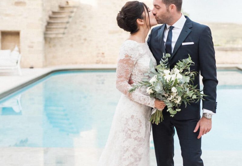 Un couple s'embrassant tendrement au bord d'une piscine dans un domaine privé, illustrant l'atmosphère romantique et sophistiquée d'un mariage de luxe. Cette scène capture l'essence d'une cérémonie grandiose en Provence, avec des éléments sur mesure pour une célébration inoubliable. Le cadre élégant, entouré de verdure, est parfait pour un mariage unique, alliant charme et raffinement. By Mademoiselle C crée des événements exceptionnels,