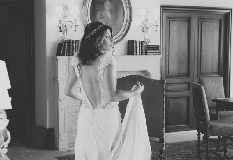 Une mariée élégante se prépare dans un somptueux domaine privé, incarnant le luxe d'un mariage sur mesure en Provence. Avec son dos nu et sa robe délicate, elle évoque une atmosphère romantique, parfaite pour une célébration grandiose. Ce cadre raffiné, avec des murs en bois et des meubles sophistiqués, souligne l'expertise de By Mademoiselle C dans l'organisation d'événements uniques.