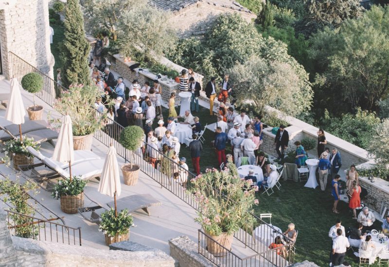 Une célébration grandiose dans un domaine privé en Provence, où des invités élégamment vêtus profitent d'une ambiance romantique et sophistiquée. Ce mariage sur mesure, organisé par By Mademoiselle C, met en valeur des espaces exceptionnels entourés de verdure luxuriante. La terrasse offre une vue imprenable sur les paysages pittoresques, créant un cadre parfait pour un événement unique.