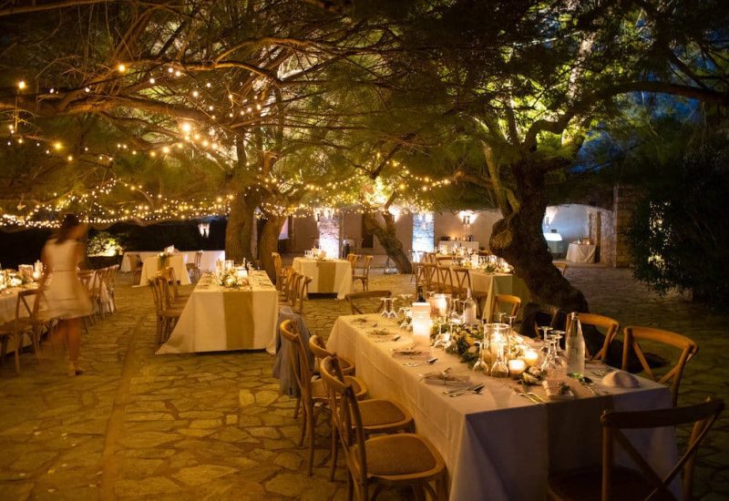 A romantic and elegant setting for a luxury wedding celebration in Provence, the French Riviera and Corsica, featuring a bespoke organization by By Mademoiselle C. Carefully laid tables under illuminated trees create an intimate and sophisticated atmosphere, ideal for a grand event. This outdoor space, surrounded by greenery, is the perfect venue for an exceptional wedding, offering a unique setting for a dream ceremony. Discover the art of