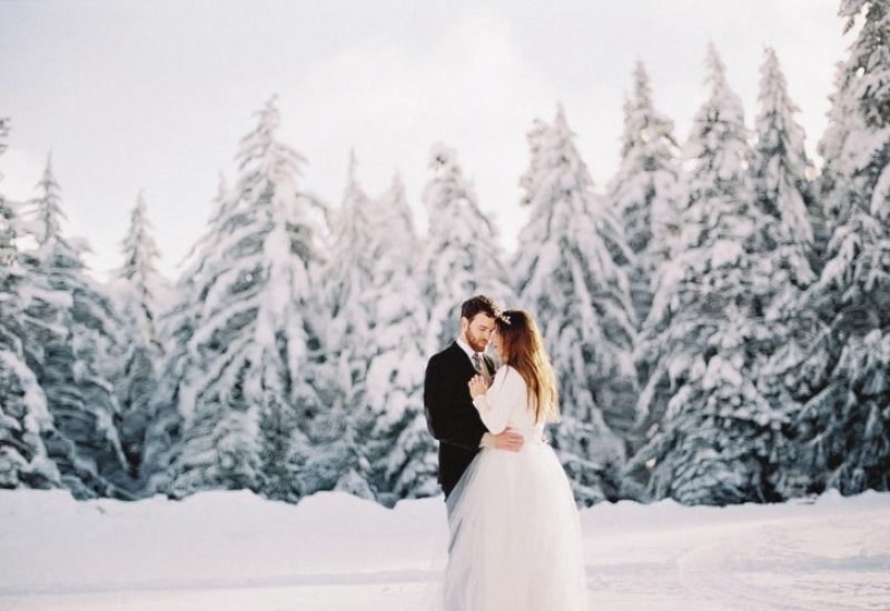 Un couple romantique s'échange des vœux dans un cadre féerique, entouré de majestueux sapins enneigés, illustrant l'expertise de By Mademoiselle C en tant que wedding planner de luxe en Provence, Côte d'Azur et Corse. Ce mariage sur mesure évoque une cérémonie grandiose, alliant sophistication et intimité, parfait pour une célébration unique. Avec un décor naturel exceptionnel, ce moment précieux reflète l'essence d'un mariage