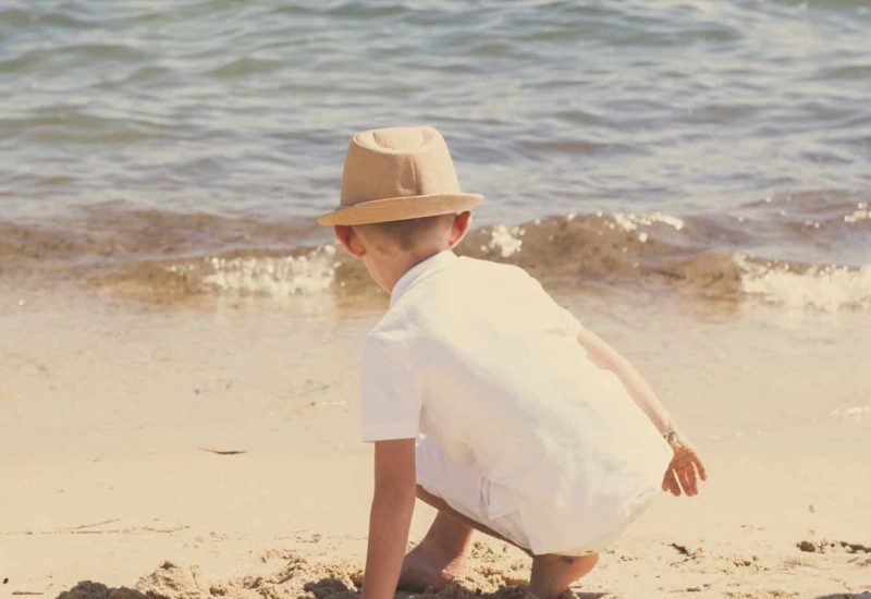 A child playing on a sandy beach, symbolizing the joyful atmosphere of a romantic ceremony. This scene evokes a luxury wedding in Provence, the French Riviera and Corsica, where every detail is carefully organized to create a unique event. The sparkling waters and natural surroundings reinforce the idea of a grand celebration in an exceptional setting. As a bespoke wedding planner, By Mademoiselle C