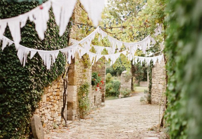 Un chemin romantique bordé de pierres anciennes et de verdure luxuriante, idéal pour une cérémonie de mariage grandiose en Provence. L'atmosphère élégante et sophistiquée de cet espace privé met en valeur l'organisation sur mesure d'un événement unique, parfait pour un mariage de luxe. Les guirlandes délicates ajoutent une touche de charme à cette célébration exceptionnelle, faisant de cet endroit un cadre rêvé pour un mariage sur mesure dans la Côte d'Azur.