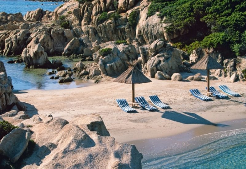 Plage isolée en Corse, idéale pour un mariage romantique, avec des transats élégants et des parasols, entourée de rochers majestueux et de végétation luxuriante. Un cadre parfait pour une célébration grandiose, offrant une expérience unique pour un événement sur mesure. By Mademoiselle C, expert en organisation de mariages de luxe, crée des souvenirs inoubliables dans des lieux d'exception en Provence, Côte d'Azur et Corse.