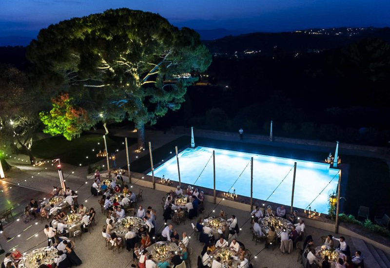 An elegant al fresco dinner on a private estate, showcasing a romantic setting under twinkling evening lights. This bespoke wedding, orchestrated by By Mademoiselle C, is a true celebration of luxury, where every detail contributes to an unforgettable experience. The illuminated swimming pool and beautifully laid tables are testimony to the exceptional organization of this unique event in Provence, the French Riviera and Corsica. This great moment of happiness, in