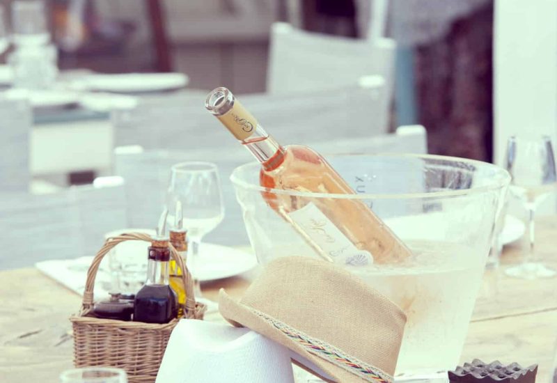 An elegant table set for a luxury wedding in Provence, the French Riviera or Corsica, adorned with stylish hats and a refreshing bottle of rosé. This romantic setting evokes a unique, bespoke celebration, perfect for a grand event on a private estate. Sparkling glasses and refined details underline By Mademoiselle C's expertise in organizing exceptional ceremonies. Whether this