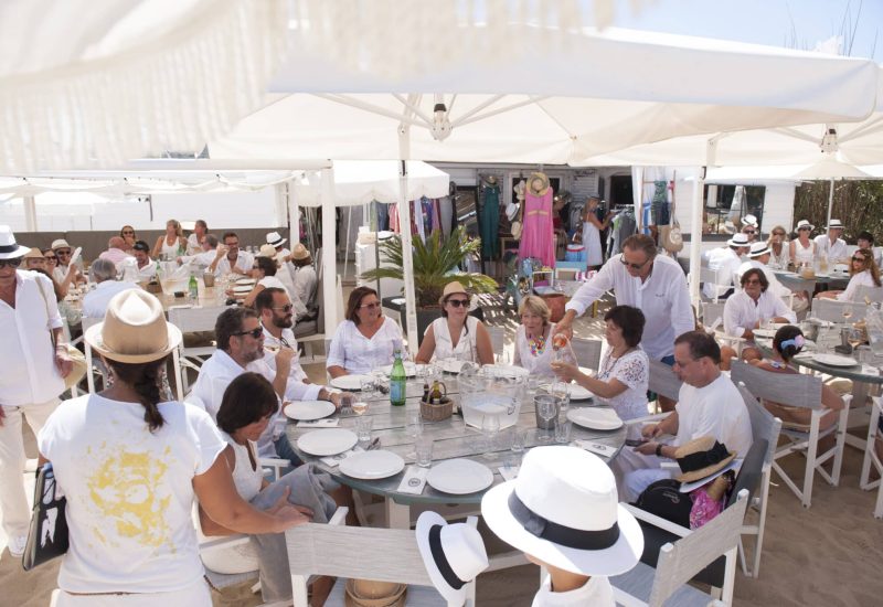 An elegant and romantic wedding event organized by By Mademoiselle C, staging a grand celebration on the beach, surrounded by guests in white. This idyllic setting, typical of the French Riviera, evokes a luxurious, made-to-measure wedding, with carefully laid tables and a convivial atmosphere. Guests, immersed in a sophisticated atmosphere, enjoy an unforgettable moment, ideal for a