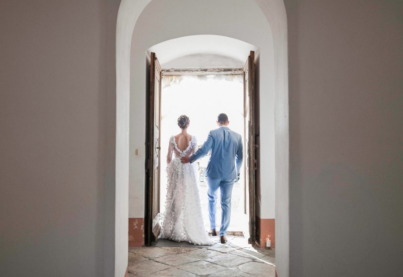 A couple holding hands, emerging from an elegant mansion, symbolizing a romantic and intimate moment, perfect for a luxury wedding in Provence, French Riviera and Corsica. This scene evokes the tailor-made organization of a grandiose ceremony on a private estate, where every detail is thought out to create a unique event. The refined, sophisticated atmosphere of this sublime venue underlines the expertise of 'By Mademoiselle C' in creating