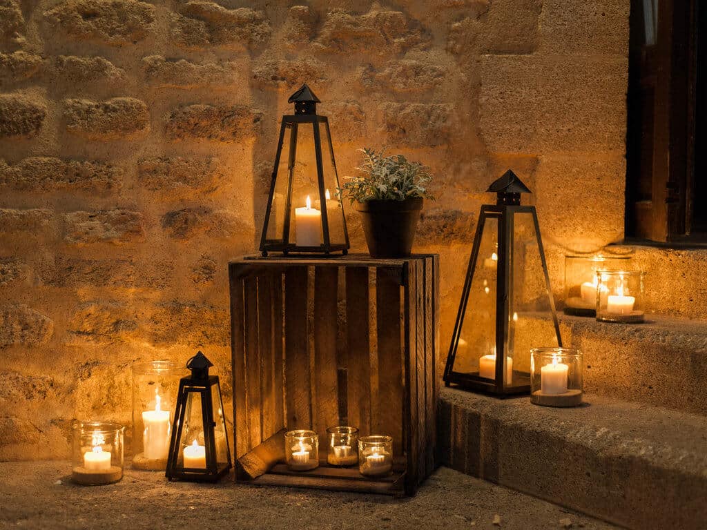 Ambiance romantique et élégante d'un mariage de luxe, mettant en avant des lanternes en fer et des bougies créant une atmosphère chaleureuse dans un domaine privé. Cette scène évoque une célébration grandiose et sur mesure, idéale pour un événement unique en Provence, Côte d'Azur ou en Corse. Le cadre sophistiqué, avec des éléments naturels et une lumière douce, est parfait pour un mariage de rêve, soulignant l'expertise de By Mademoiselle C